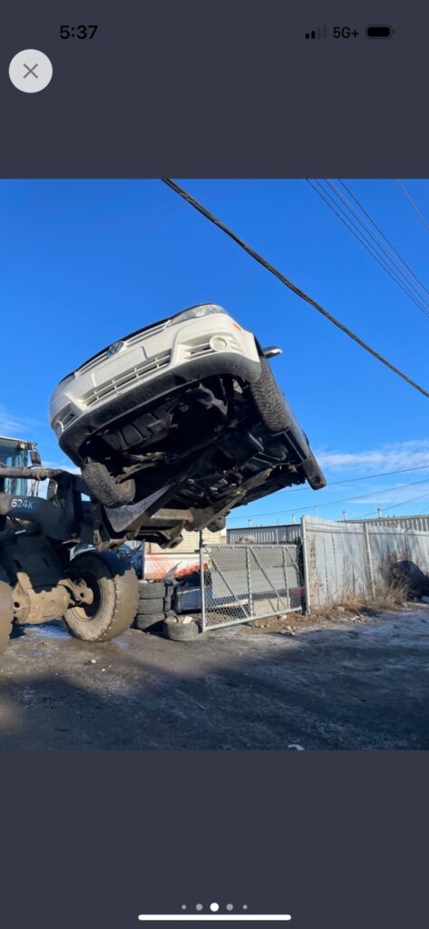 lift truck moving a junk car